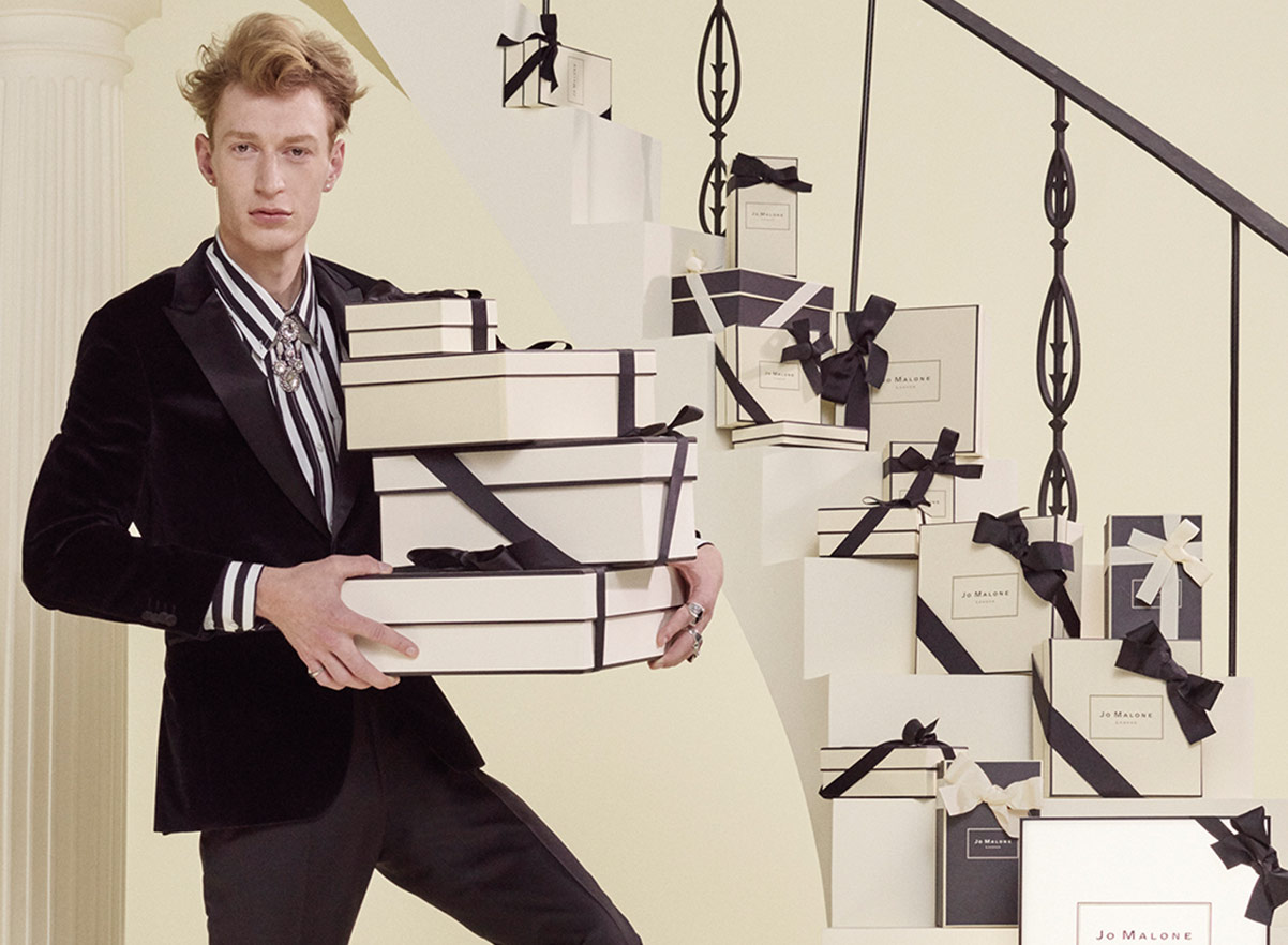 Man holding Jo Malone London gift boxes by some stairs